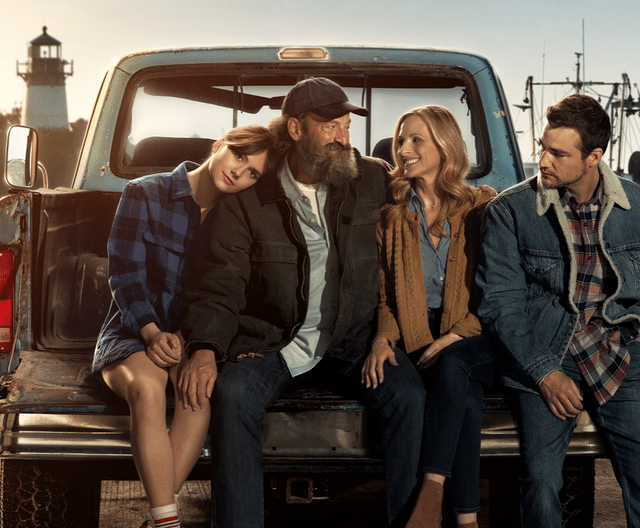 Photo of two men and two women sitting on a truck bed.